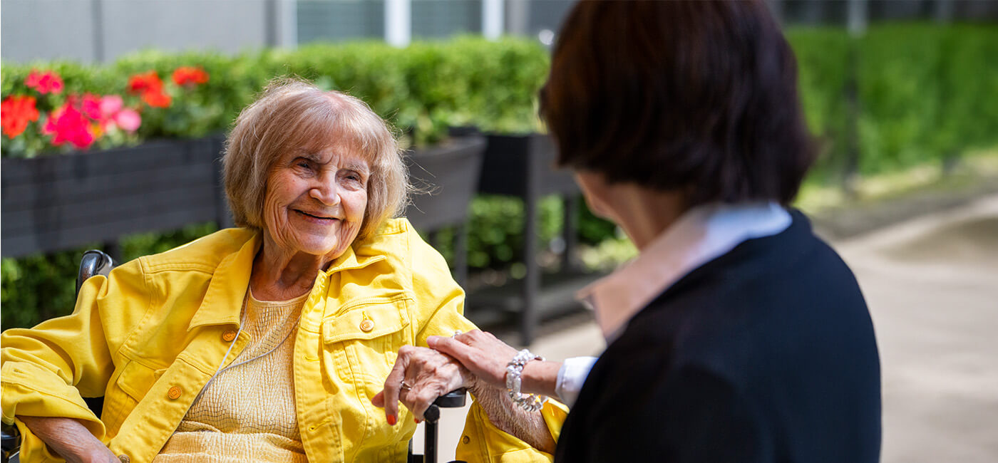 Adult woman holds senior's hand