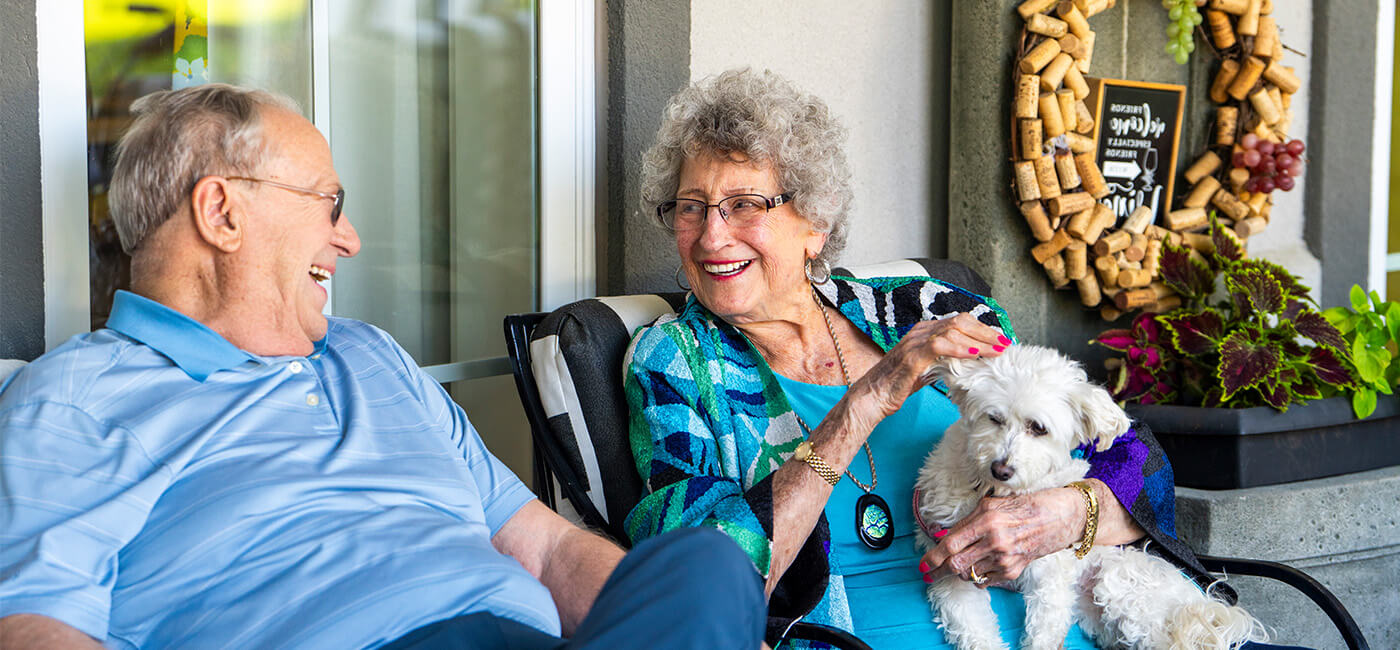 senior couple holding a dog on their porch