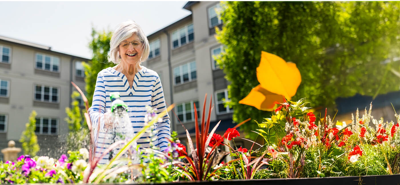 Senior woman watering flowers in a garden