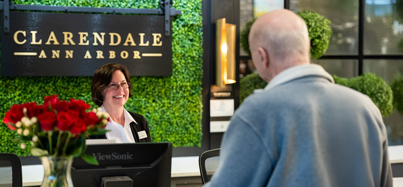 Senior man talking to receptionist at Clarendale Ann Arbor